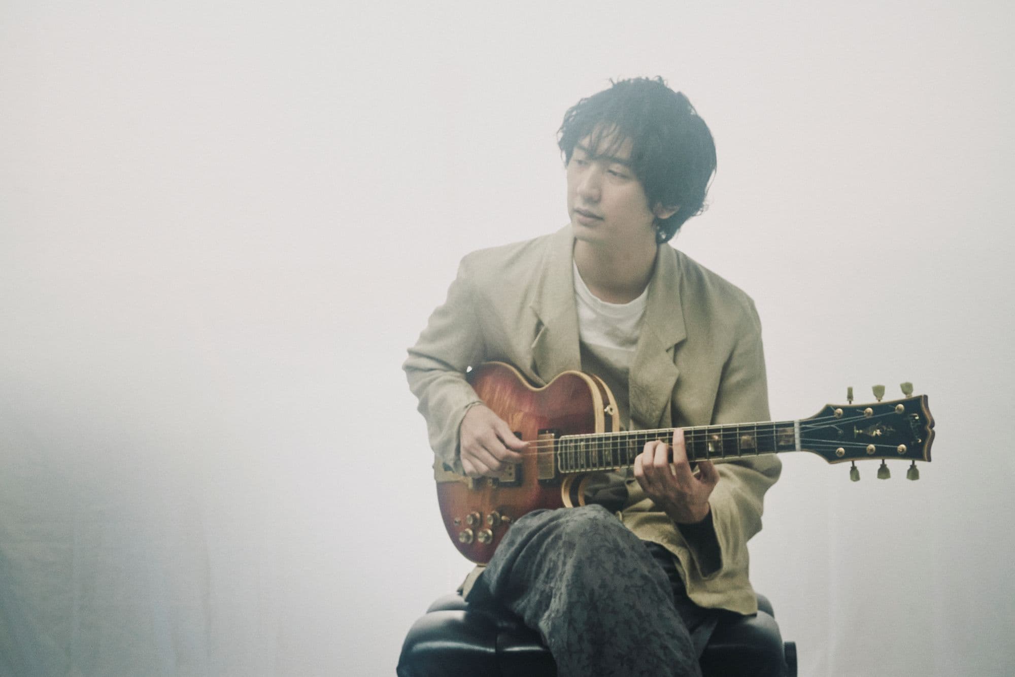 A man sitting down in a studio with a guitar